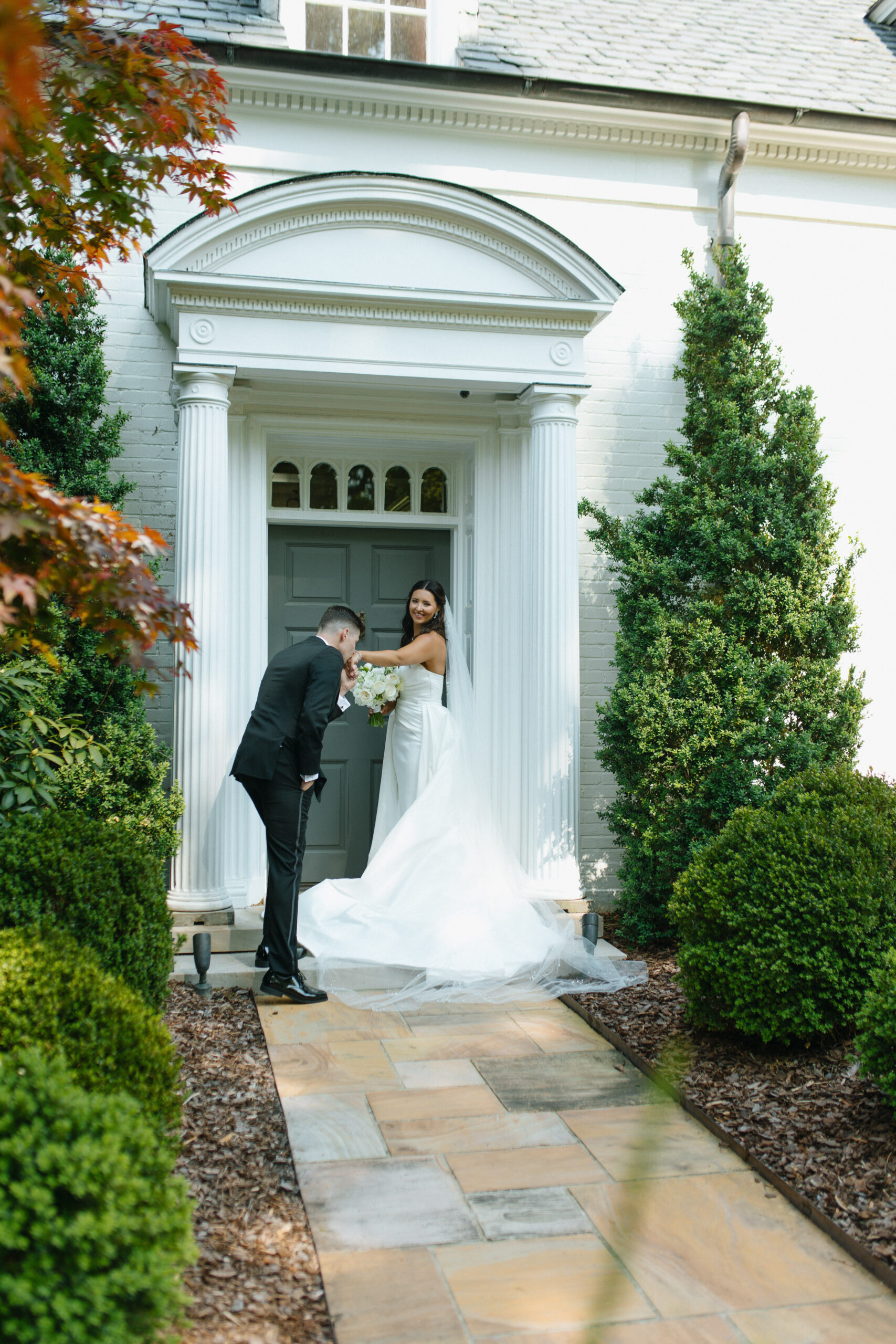 couple in front of their wedding venue during their sunset portraits with the groom holding the brides hand