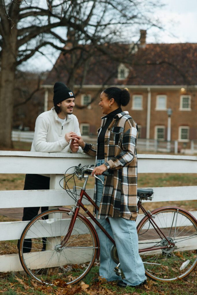 couple splitting the fence playing with their hands together 